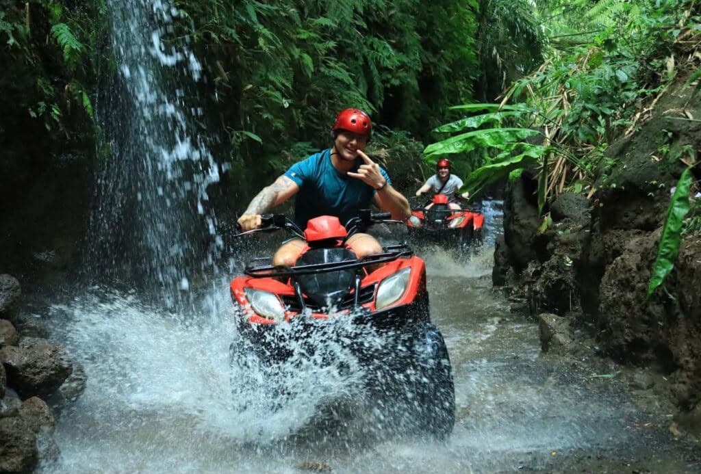 Quad bike ATV splashing through river crossing in tropical Bali jungle